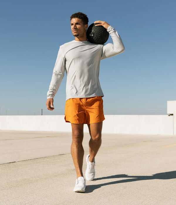 Man performing a strength exercise in a modern gym with orange light.